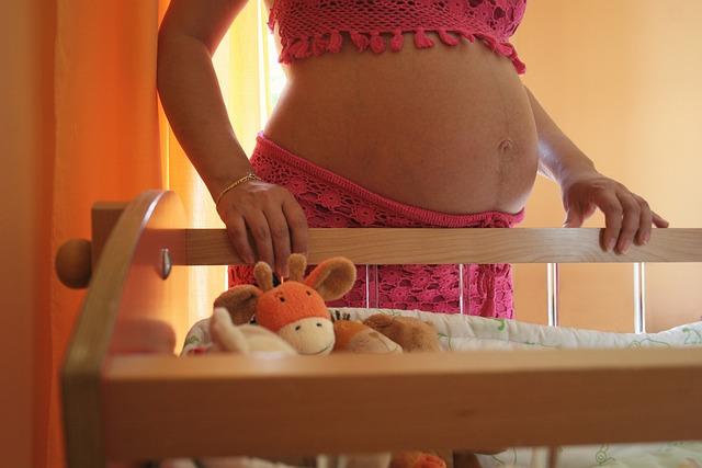 kobieta w ciąży przy łóżeczku dla dziecka